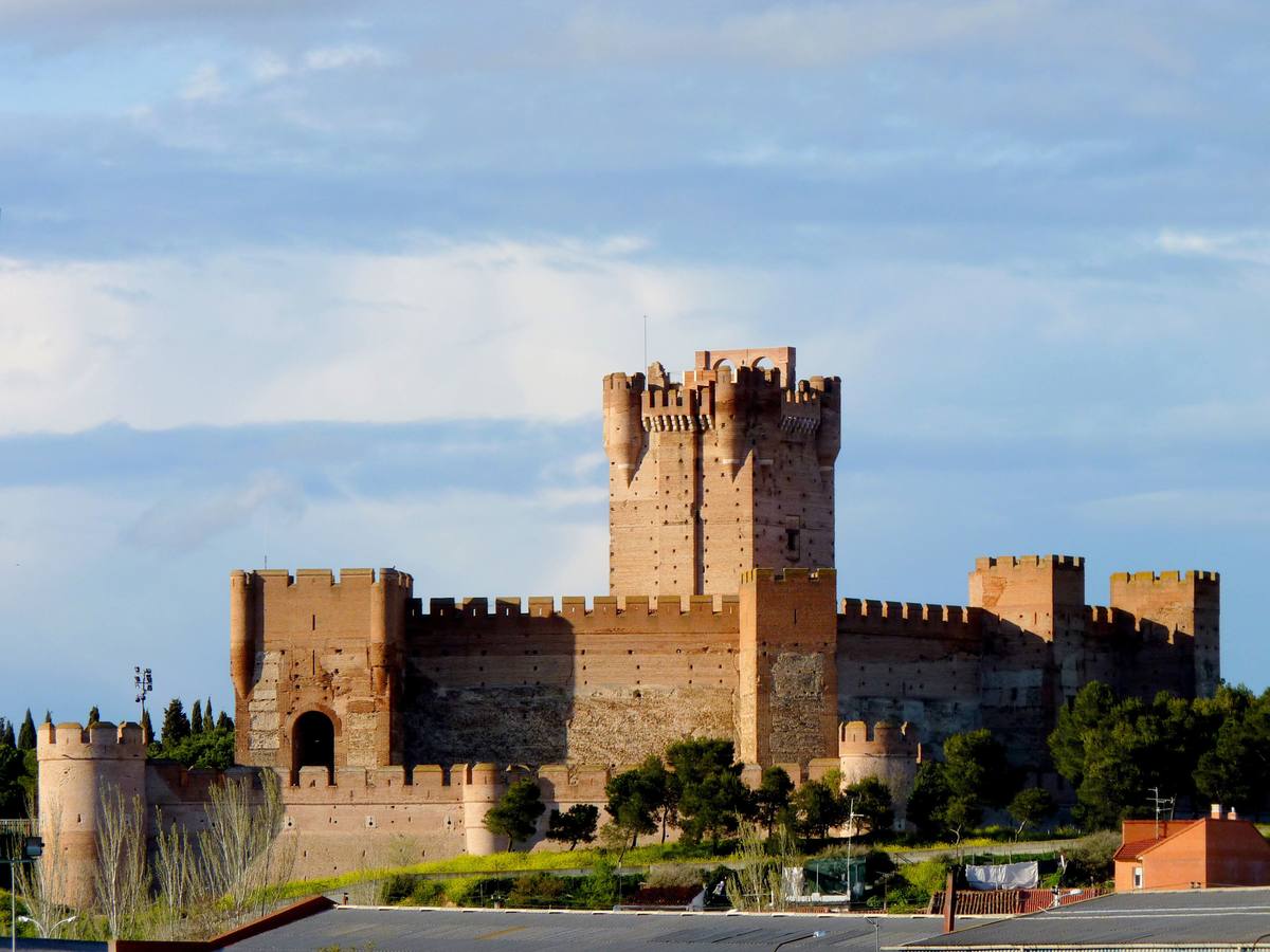 Castillo de La Mota. Medina del Campo (Valladolid). Situado en una elevación del terreno (mota), domina la villa y toda su extensa comarca. De él arrancaba un recinto amurallado, ampliado en tres ocasiones, que abrazaba la población, y del cual subsisten algunos restos. Se edificó con el característico ladrillo rojizo propio de la zona, empleándose la piedra únicamente para pequeños detalles, como troneras, escudos, etc.