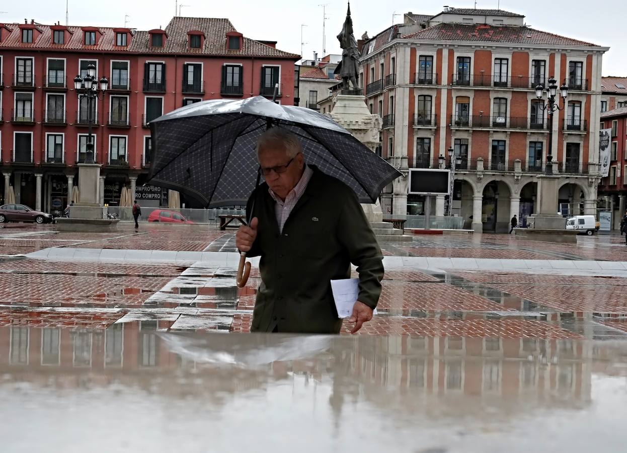 Un hombre se protege de la lluvia en la Plaza Mayor de Valladolid.