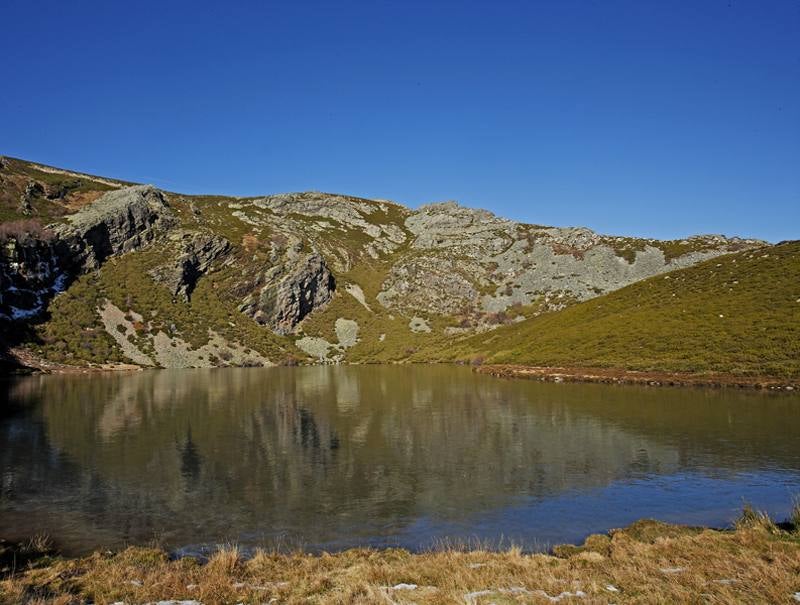 Lago de Truchillas (León). Se encuentra en la Sierra de la Cabrera, en el suroeste de León, lindando con Zamora. Su origen es consecuencia de la intensa erosión que los hielos cuaternarios llevaron a cabo en las vertientes septentrionales de estas antiguas montañas compuestas, principalmente, por materiales pizarrosos y cuarcíticos. Las laderas en las que está enclavado el lago, declarado Monumento Natural en 1990, aparecen cubiertas por un denso matorral de brezo, retama y enebro rastrero.