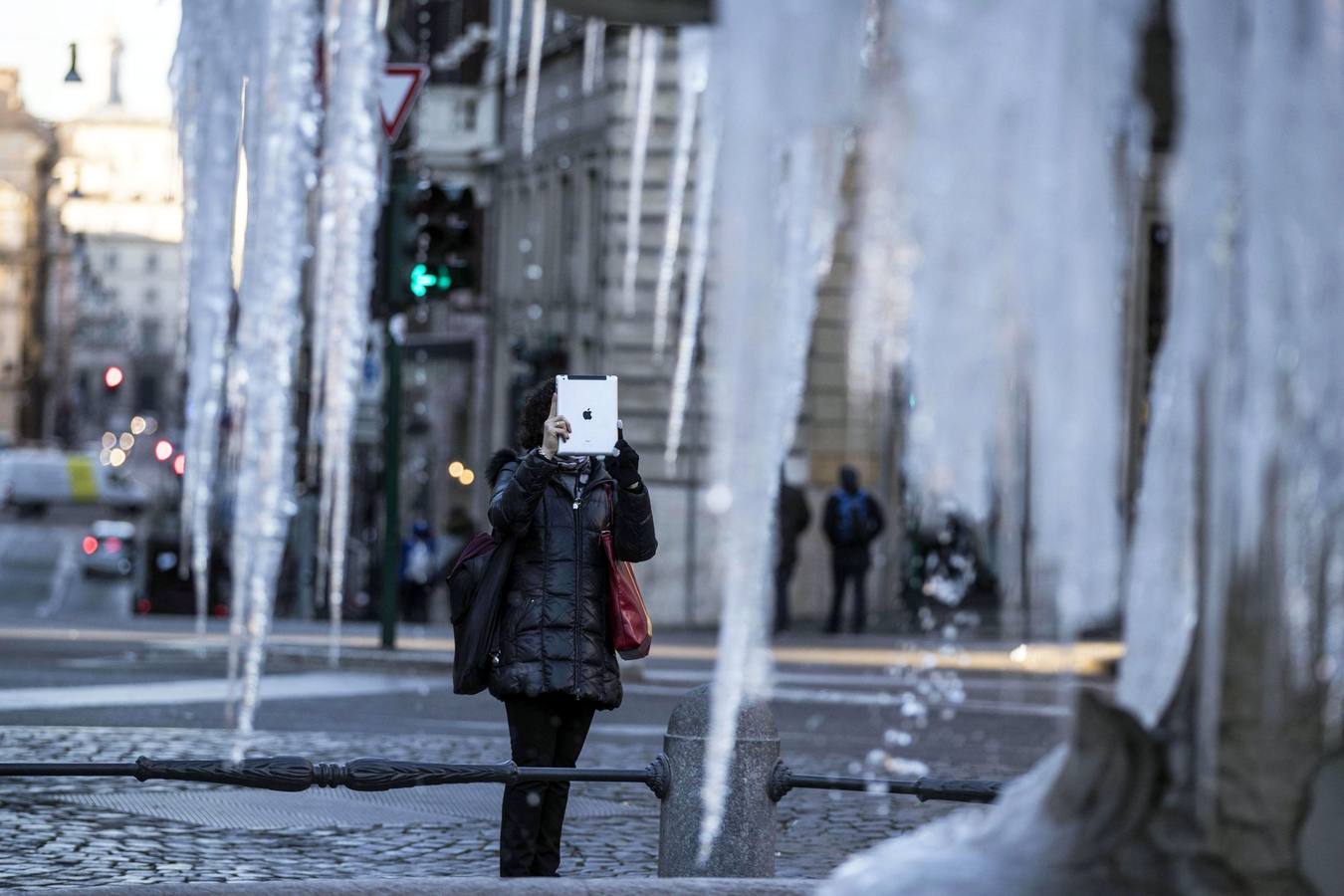 Una mujer fotografía la Fuente de Tritón helada en la plaza de Barberini en Roma.