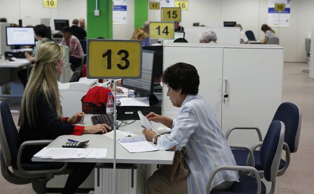 Una trabajadora atiende a una mujer en la oficina de la Agencia Tributaria en Valladolid.