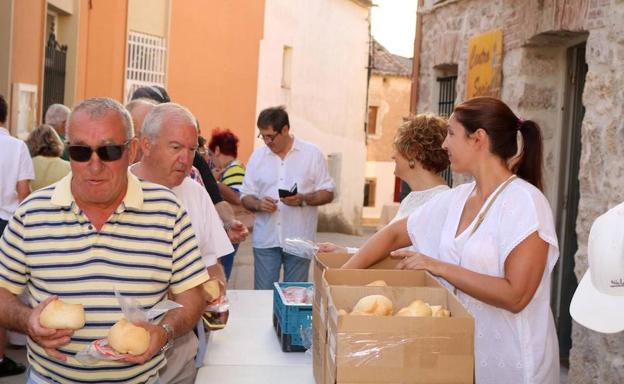 Los vecinos recogen las raciones de pan y queso.