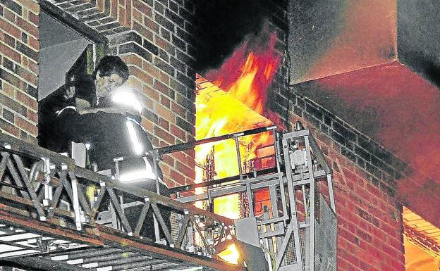 Imagen principal - Arriba, un bombero ayuda a una de las vecinas. Sobre estas líneas, los bomberos caminan entre los escombros y vecinos desalojados. 