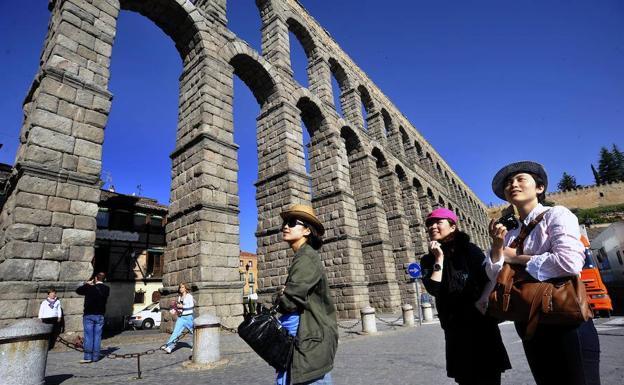 Tres turistas chinas pasean delante del Acueducto de Segovia. 