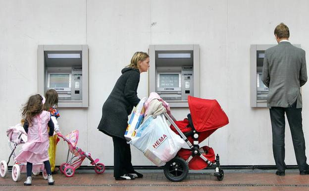 Algunos clientes utilizan los cajeros automáticos de una oficina bancaria.