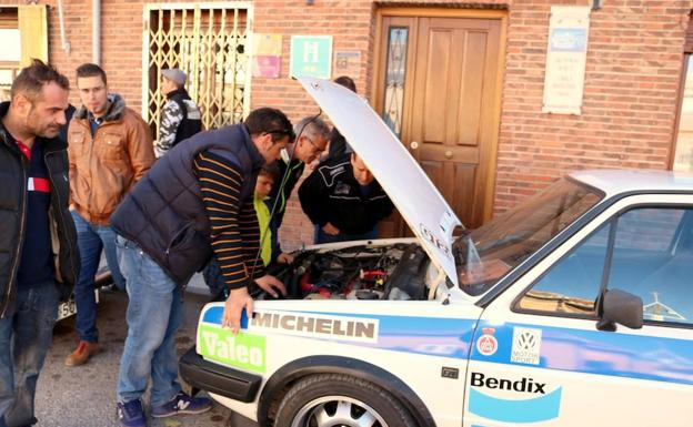 Varios vecios observan el motor de un coche participante.