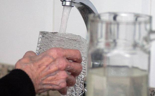 Una mujer coge agua de un grifo de su casa. 