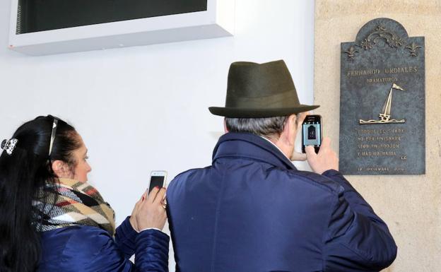 Dos personas fotografían la placa en memoria de Fernando Urdiales. 