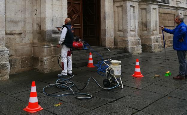 Un operarios procede a eliminar la pintada de la fachada. 