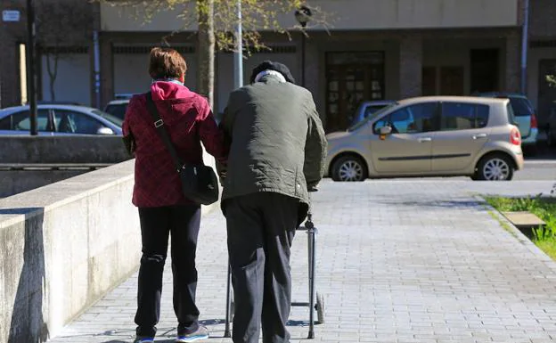 Una persona mayor camina por una acera.