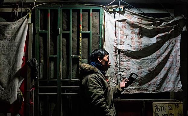 Un hombre mira su teléfono en Shanghái.