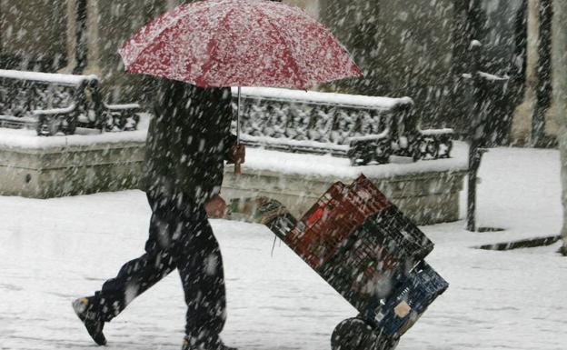 Un repartidor se protege de la nieve mientras realiza su trabajo.