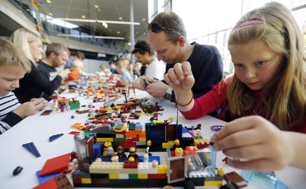 Niños y adultos arman juguetes con piezas durante el Festival Lego. 
