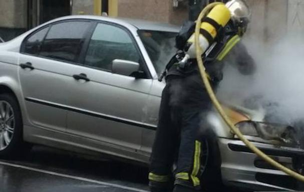 Un bomberos apaga el fuego en el vehículo.
