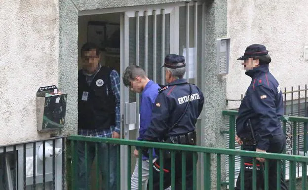 Agentes de la Ertzaintza acompañan al tercer detenido en el registro de su domicilio, en Otxarkoaga. 