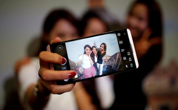 Tres mujeres se fotografían con su teléfono. 