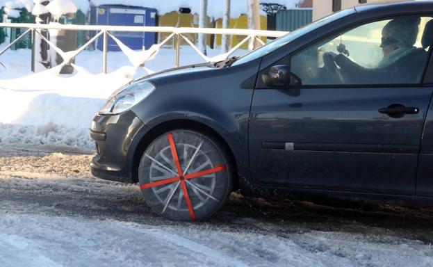 Un coche circula con cadenas por una calle.