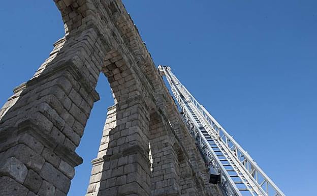Los bomberos inspeccionan desde la cesta de la autoescala el muro superior del Acueducto. 