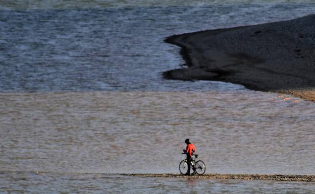 Un ciclista toma fotos en el borde del pantano de Aguilar. 