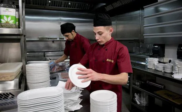 Dos jóvenes trabajan en la cocina de un restaurante.