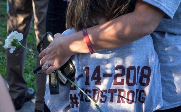 Una madre abraza a su hija mientras padres y estudiantes llegan a la escuela del tiroteo de Parkland. 