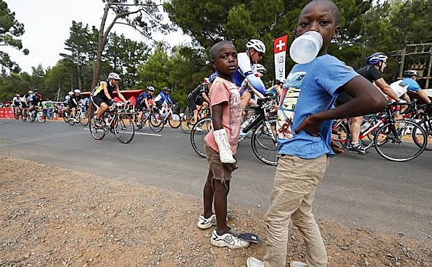 Dos niños observan el paso de una carrera ciclista en Ciudad del Cabo. 