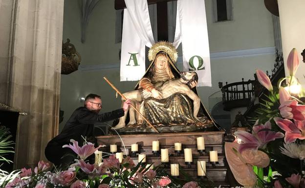 Un cofrade coloca el bastón de mando de la alcaldesa sobre el tablero de la imagen de la Virgen de las Angustias, en el interior del templo. 