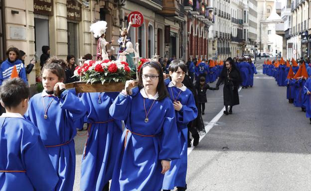 Varios escolares portan un pequeño paso en andas durante la procesión infantil. 