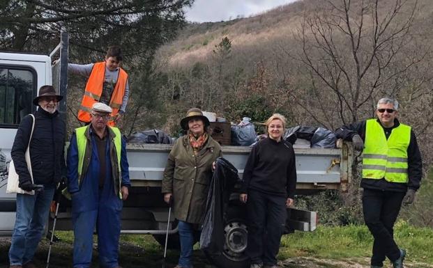 Los participantes en la recogida de residuos junto al camión lleno de la basura retirada.