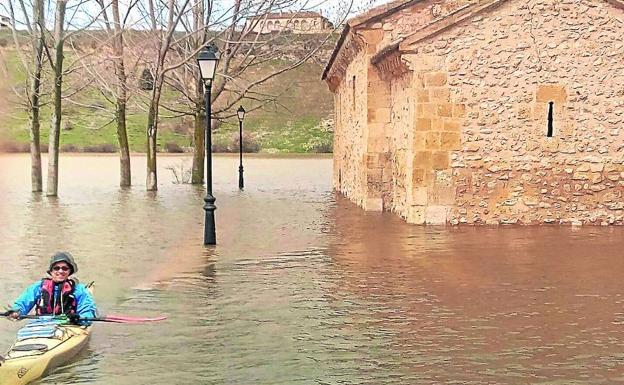 Una mujer navega en una piragua junto a la ermita de la Vera Cruz de Maderuelo, hace unos días.