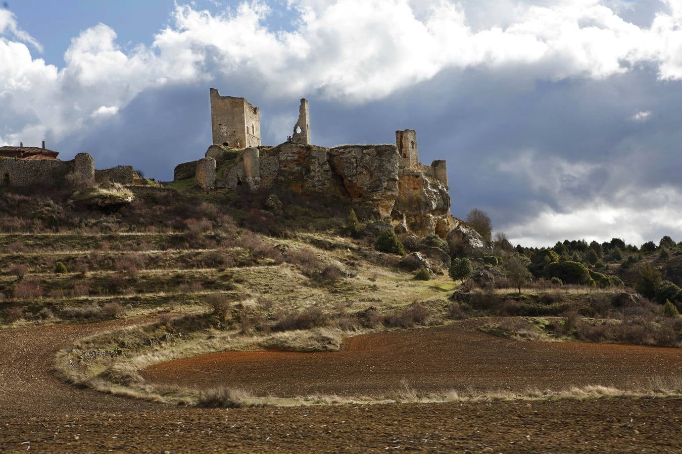 Calatañazor (Soria). Pueblo amurallado que en su parte más alta contempla el Castillo. Desde su Torre del Homenaje se divisa todo el valle. Las construcciones se aglutinan en torno a su calle principal, porticada, donde se observan construcciones típicas de Tierra de Pinares, creadas con madera, barro y piedra. Típicas también sus chimeneas de teja partida. Un lugar original y digno de ver.