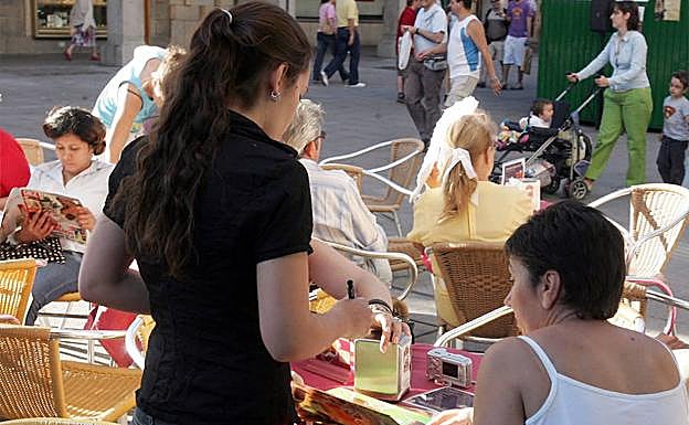 Una camarera atiende a unos clientes en una terraza de Segovia. 