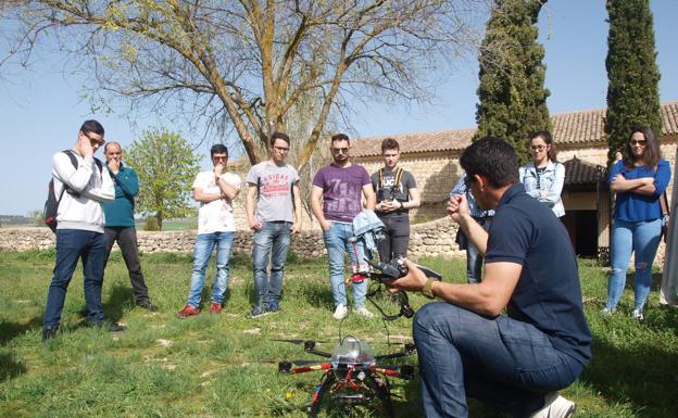 Varios alumnos prestan atención, a las puertas de la ermita, a las indicaciones de uso del dron.