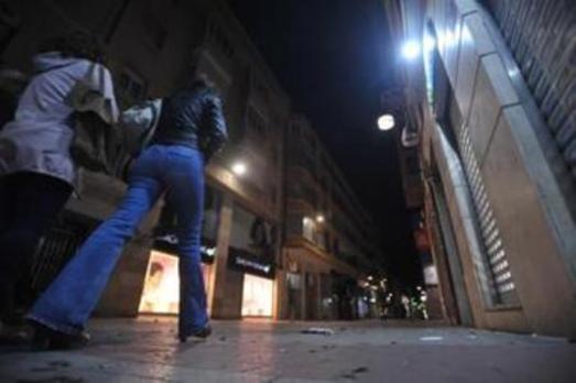 Dos mujeres caminan por la calle Mantería de noche. 