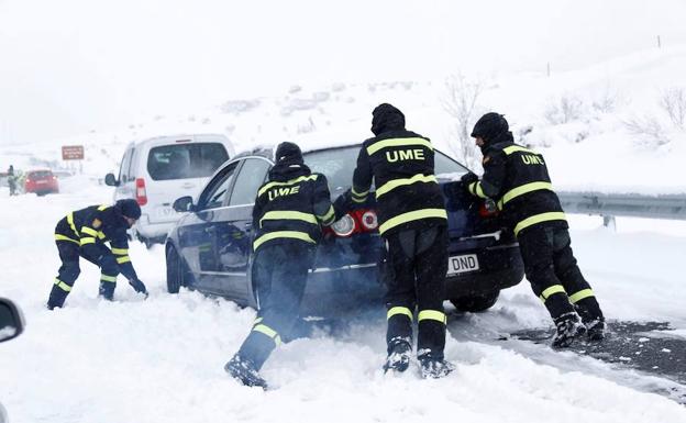 Militares ayudan a mover un coche en la nevada de la AP-6 del fin de semana de Reyes. 