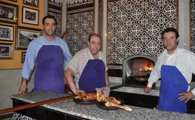 Javier Cristóbal, junto a sus hijos Enrique y Roberto, con el célebre asado que ha dado fama al Asador Nazareno, en Roa (Burgos). 