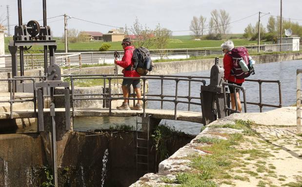 Dos peregrinos cruzan una esclusa de Frómista el pasado mes de abril.