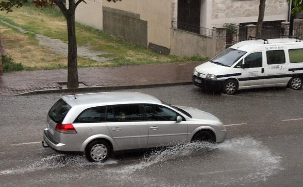 Un coche transita por una de las calles de Cuéllar inundadas por la lluvia caída este lunes. 