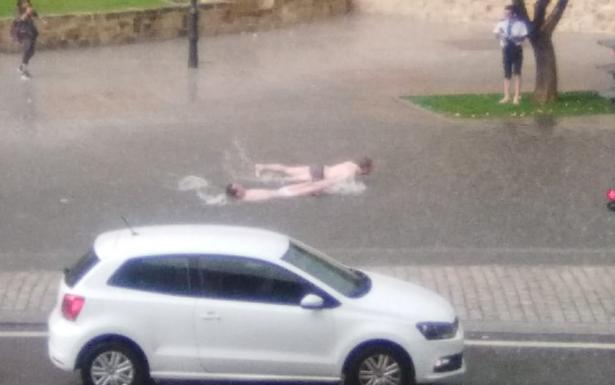 Dos personas simulan que nadan durante la tromba de agua de ayer en Salamanca.