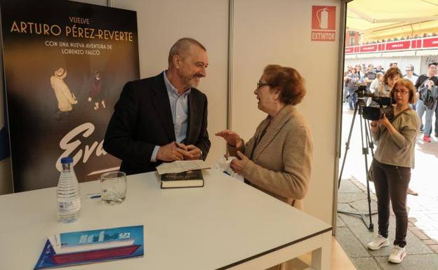 Arturo Pérez-Reverte charla con una lectora en la caseta de firmas de la Plaza Mayor. 