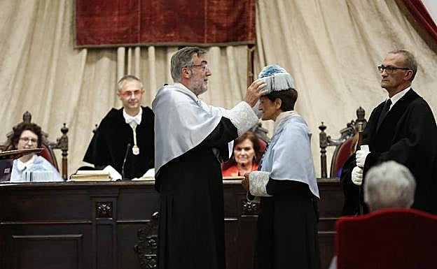 Cortina recibe el birrete ante el rector y la viepresidenta del Gobierno.