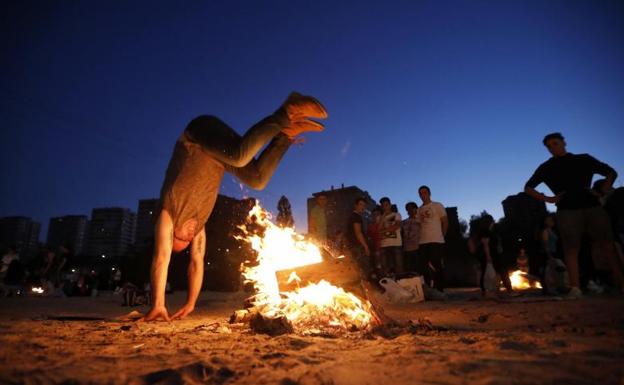 Un hombre salta una hoguera en la playa de las Moreras. 