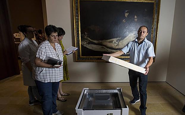 Un operario se dispone a sacar el cuadro en presencia de Carmen Espinosa. 