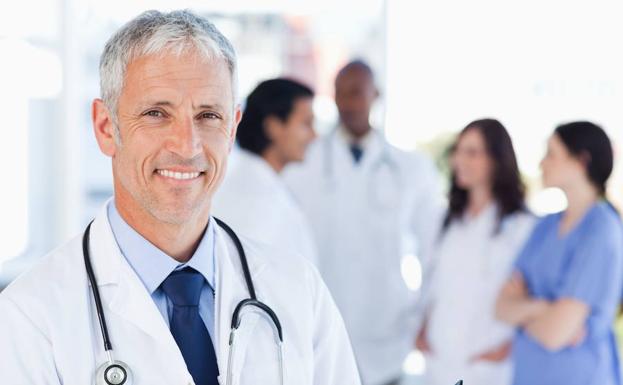 Un médico sonríe junto a varios miembros de su equipo. 