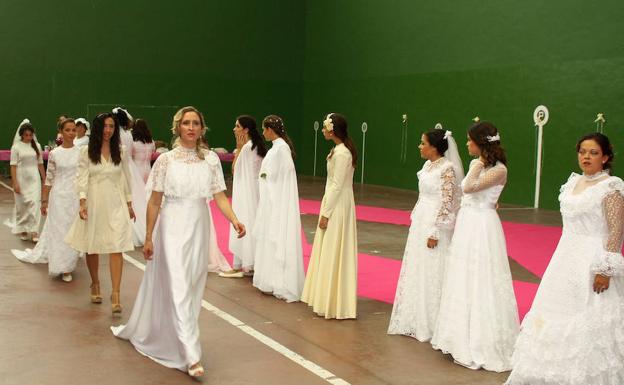 Varias mujeres desfilan con trajes nupciales cedidos por vecinas de la zona. 