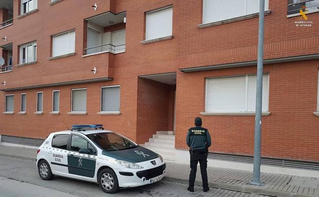 Un agente de la Guardia Civil delante de un bloque de viviendas. 
