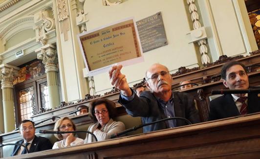 Carlos Fernández muestra a la bancada socialista una copia del título que tiene Óscar Puente. 