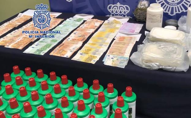 Botes con el aceite base para fabricar speed, dinero y droga incautada por la Policía Nacional.