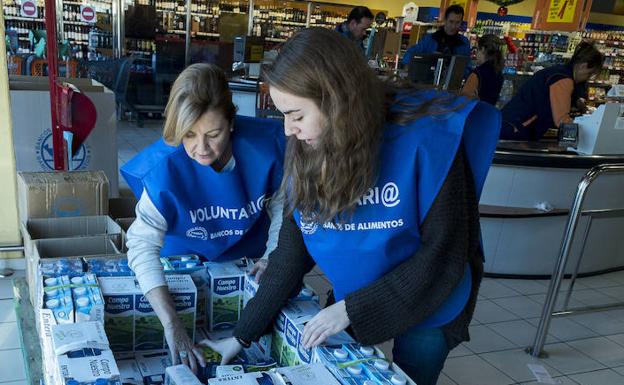 Voluntarias del Banco de Alimentos colocan los productos recogidos en un supermercado.