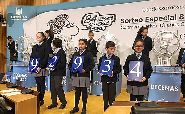 Los niños del colegio de San Ildefonso muestran el número del primer premio.